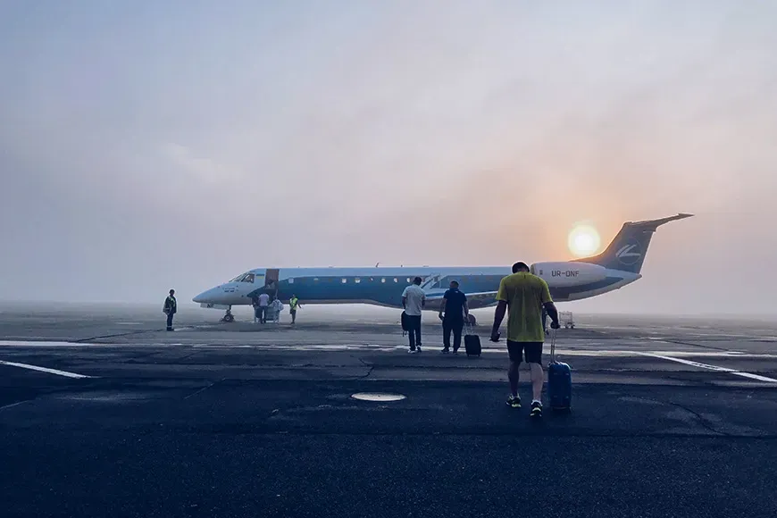 sunrise man boarding plane rolling luggage